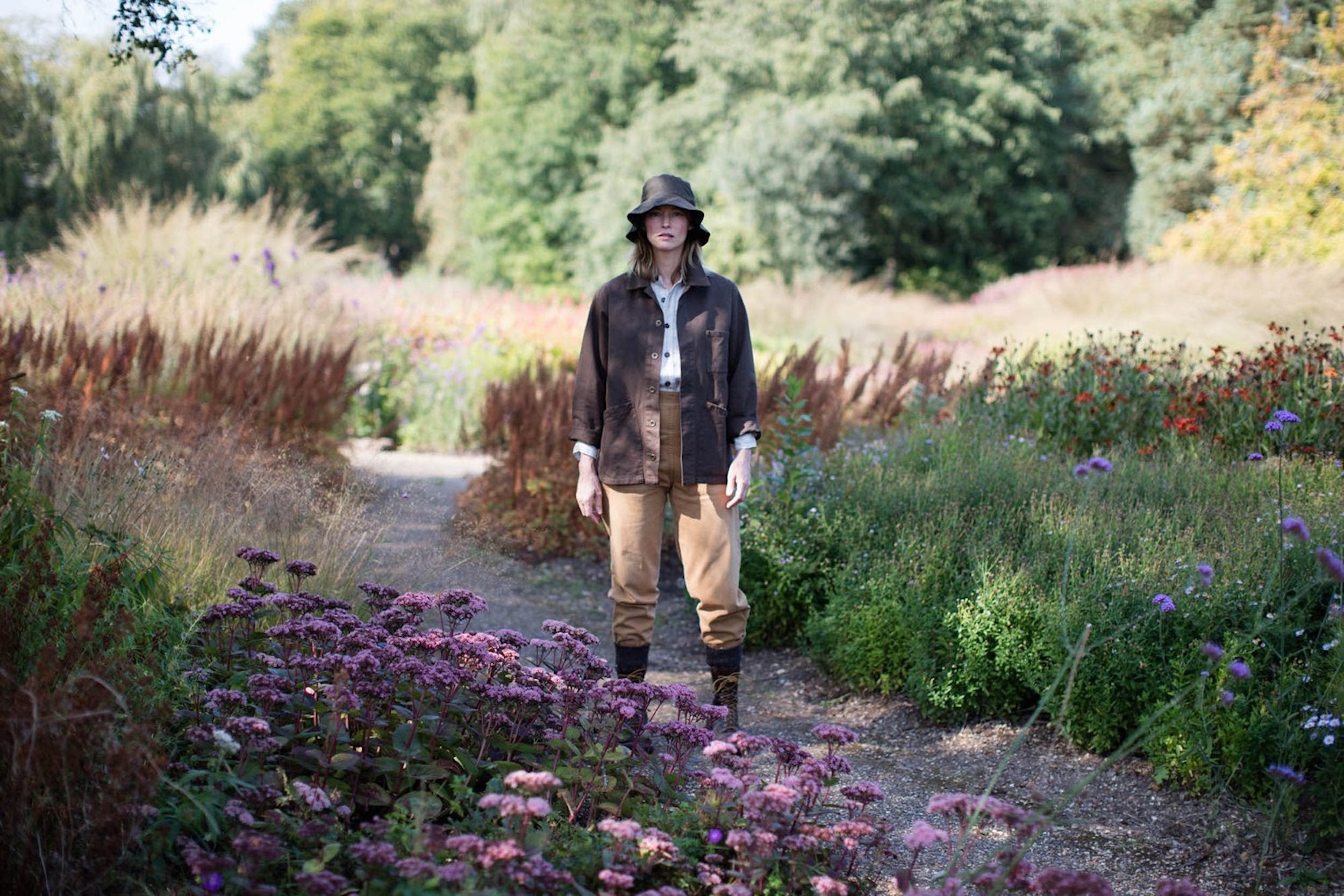 Woman wears Carrier Company Waxed Cotton Hat in Olive with Olive Work Jacket and Tan Work Trousers