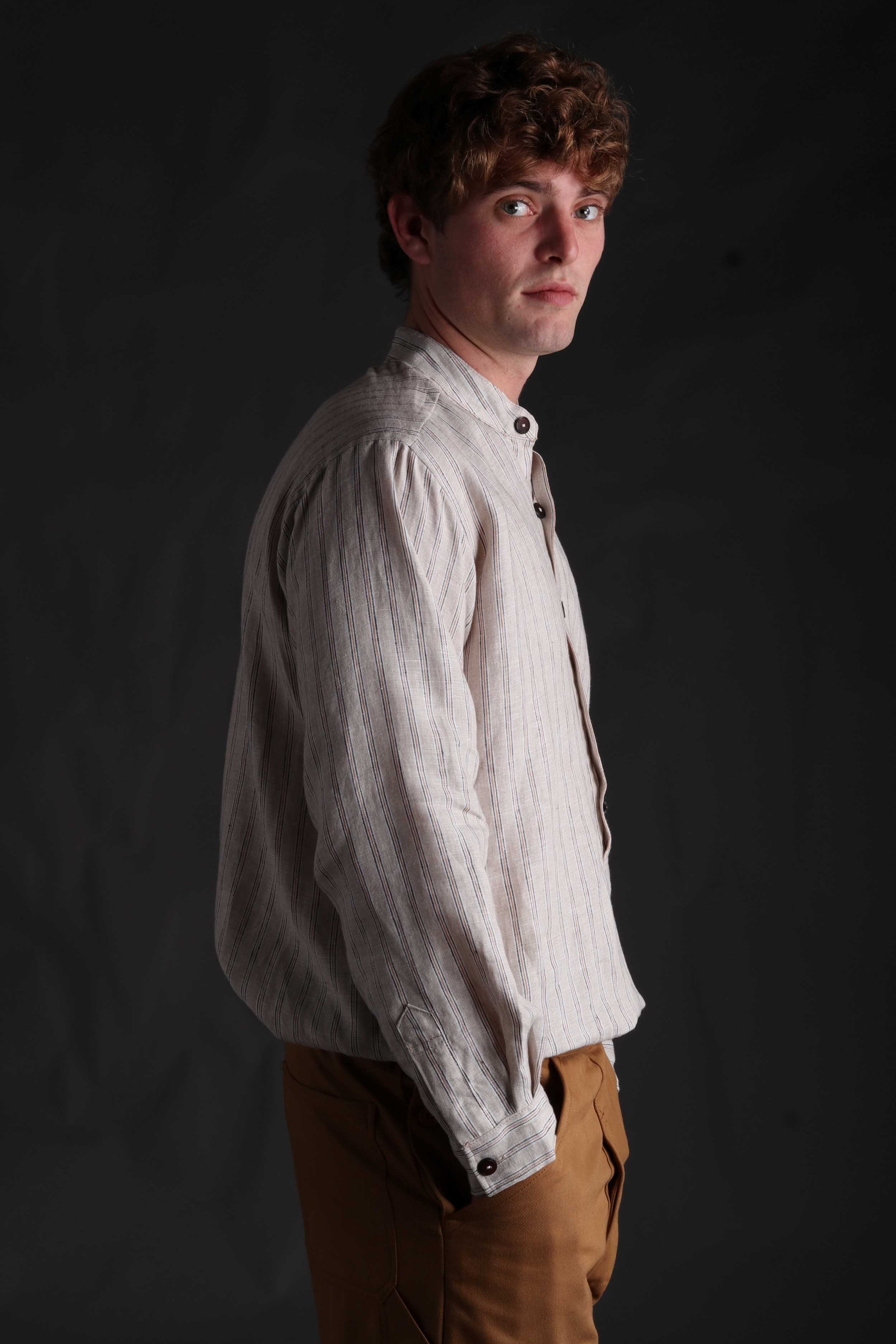 Man wears Carrier Company Collarless Shirt in Natural Linen with Tan Work Trousers
