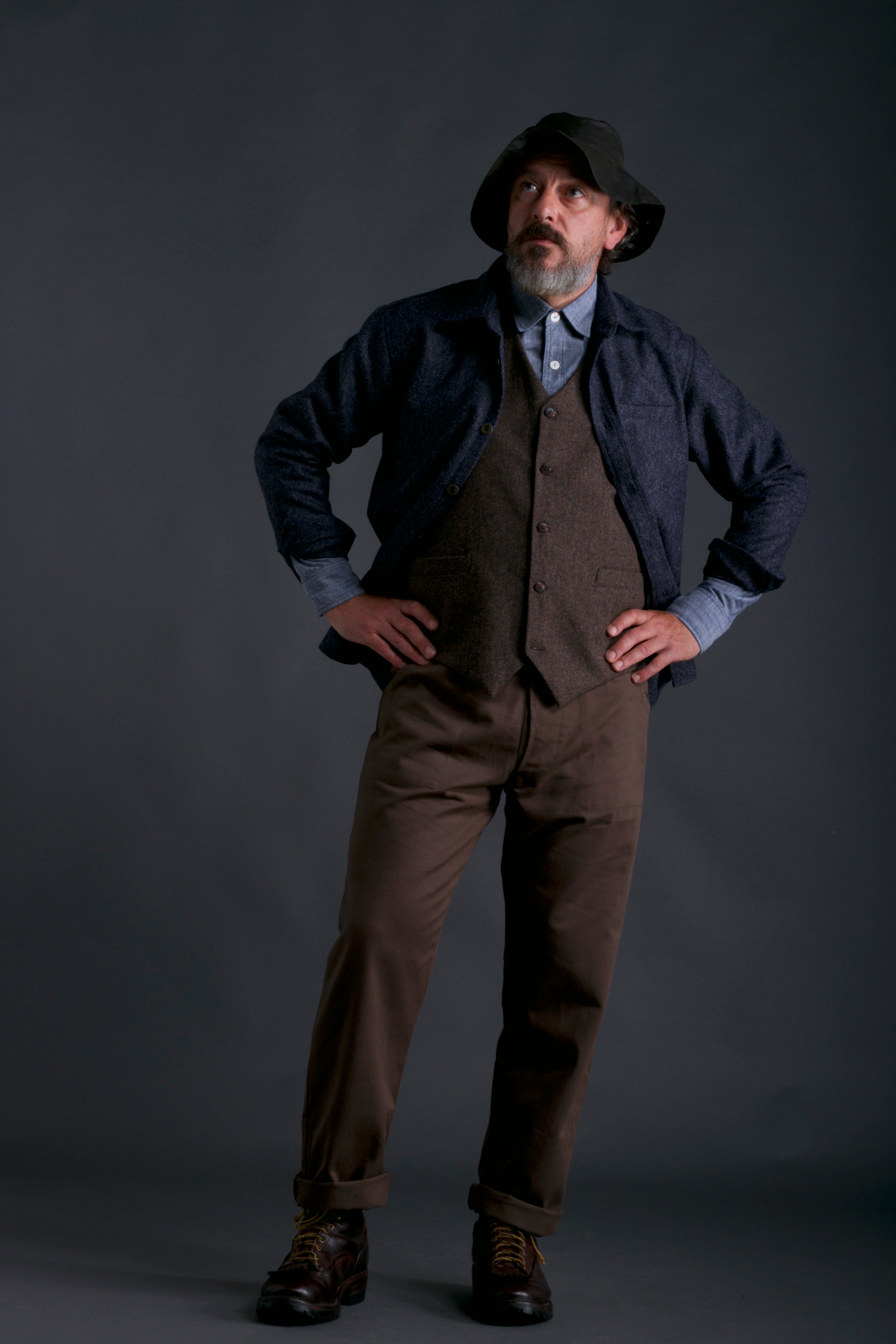 Msn wears Carrier Company Men's Wool Waistcoat in Ginger/Brown Herringbone with Olive Dungarees, Chambray Shirt and Wool Overshirt