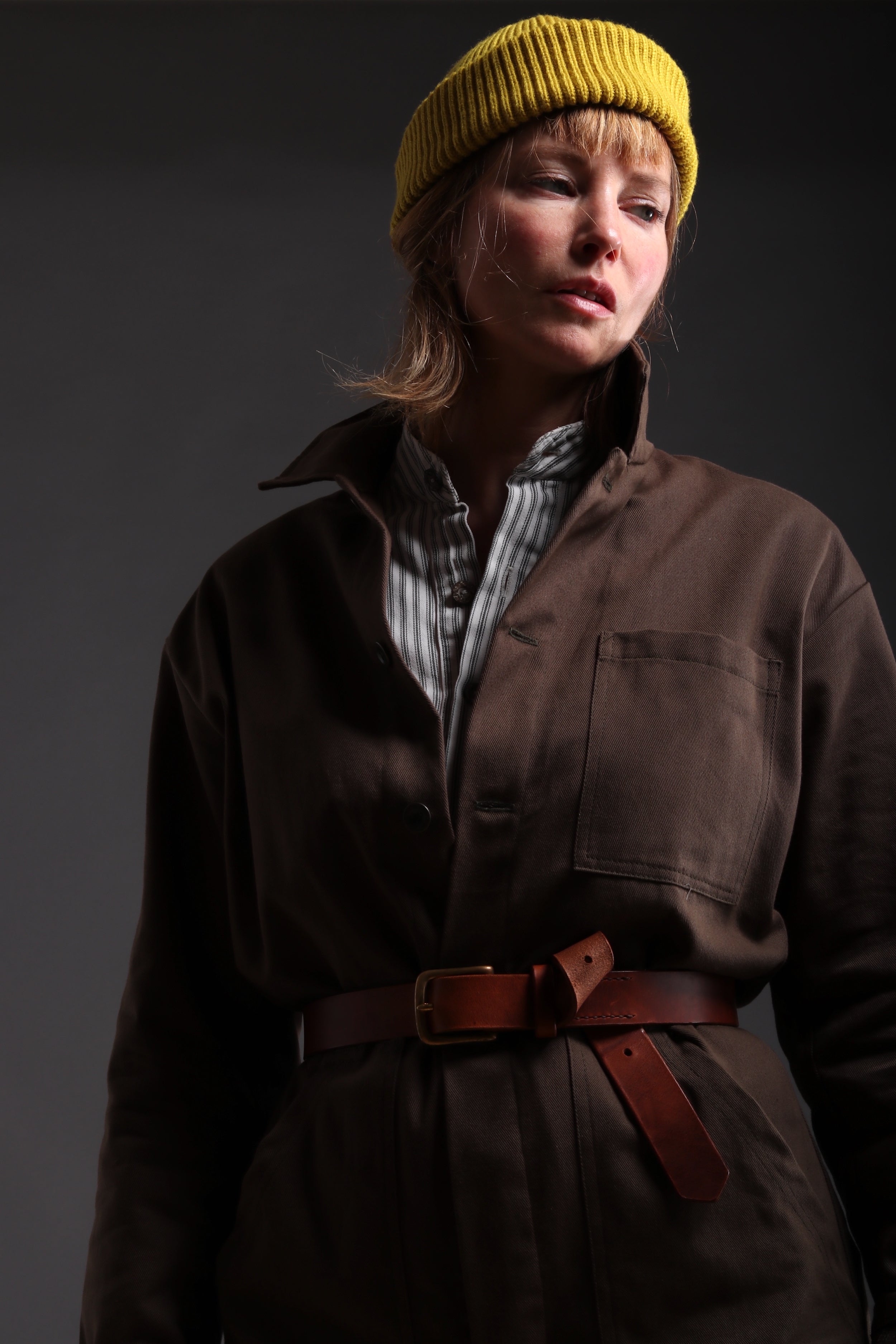 Sienna wears Carrier Company Boiler Suit in Olive Drill with Collarless Work Shirt in Ticking, Wool Hat and Chestnut Leather Belt